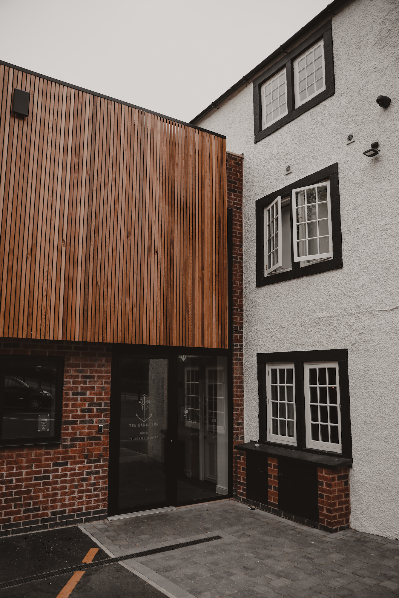 glass doors to an old white building with a contemporary wooden extension